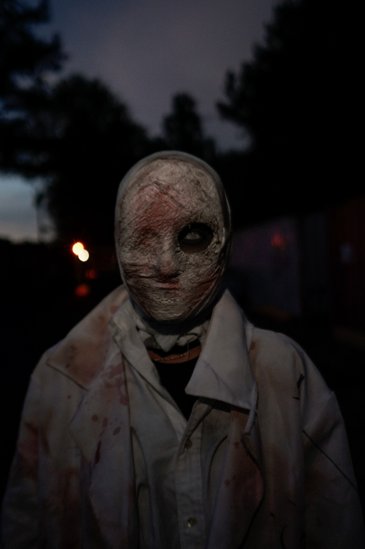 Exillium — masked figure in bloodied lab coat at dusk